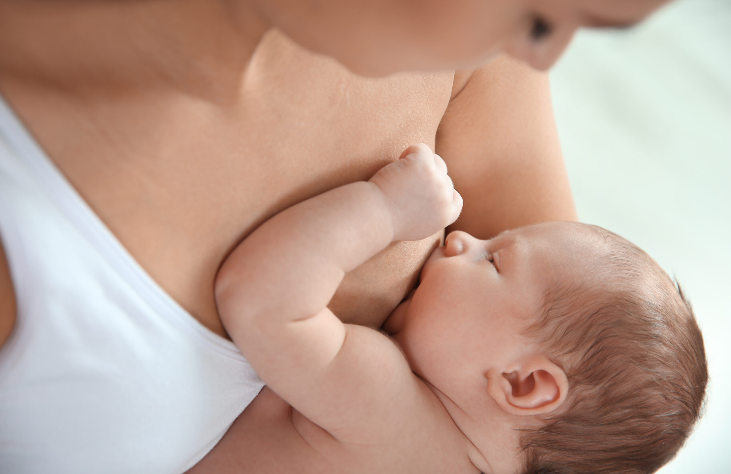 Young,Woman,Breastfeeding,Her,Baby,On,Light,Background,,Closeup